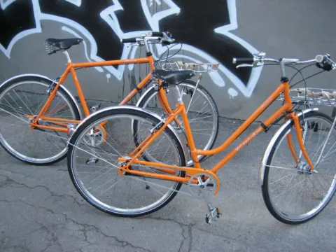 Zwei orangefarbene Räder nebeneinander, eines mit Diamant-, eines mit Trapezrahmen