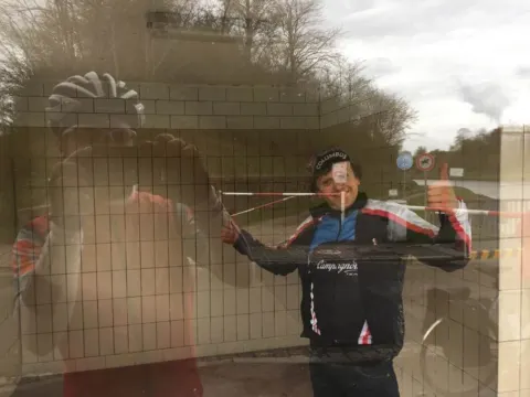 Ein Radfahrer spiegelt sich in einer Fensterscheibe und macht ein Selfie