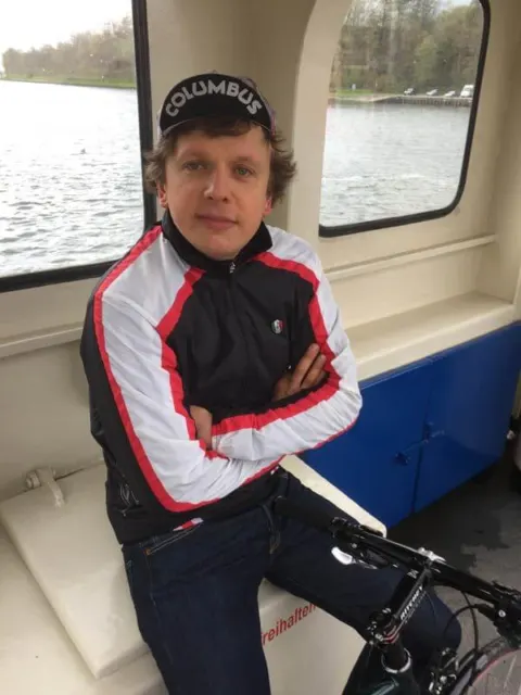 Ein Fahrer mit Rennmütze sitzt mit seinem Rad in der Kabine einer Fähre