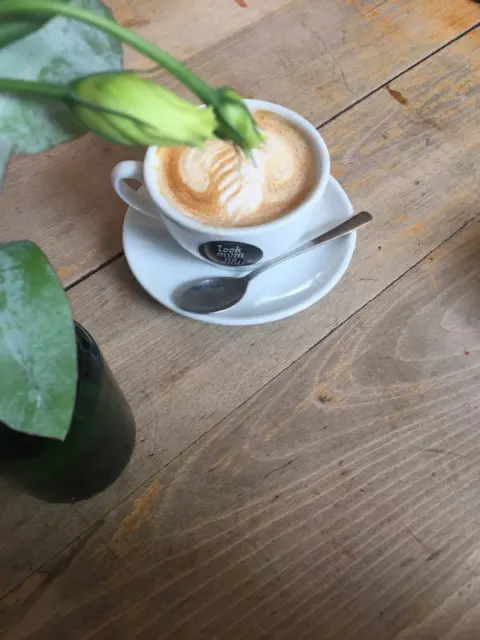 Ein Cappuccino mit Milchschaummuster auf einem Holztisch