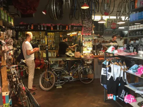 Ein Fahrradladen mit Rädern, Trikots und Zubehör dicht an dicht