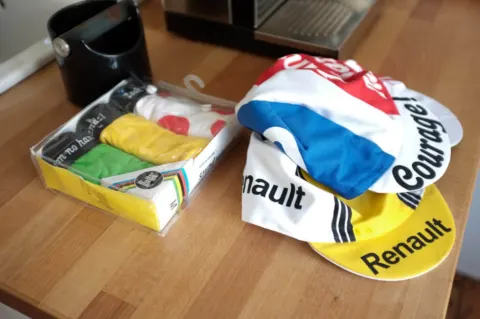 Zwei alte Rennmützen von Renault und Peugeot auf einem Tisch