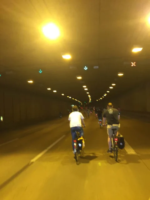 Zwei Radfahrende in einem gelb beleuchteten Straßentunnel