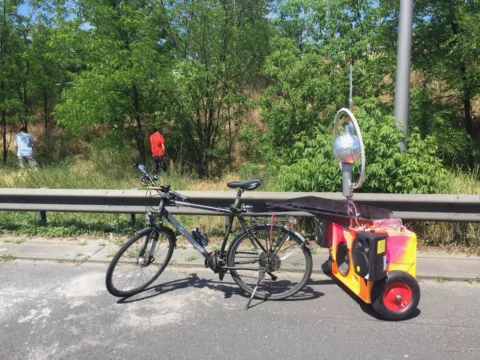 Ein Rad mit selbstgebautem Anhänger und Musikanlage steht an der Leitplanke
