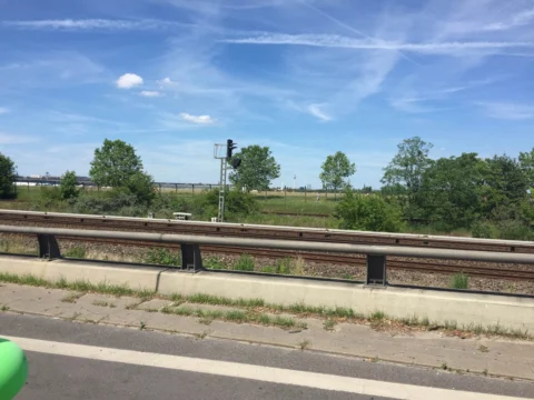 Leere Autobahnfahrbahnen mit Leitplanke, am Rand ein grüner Luftballon