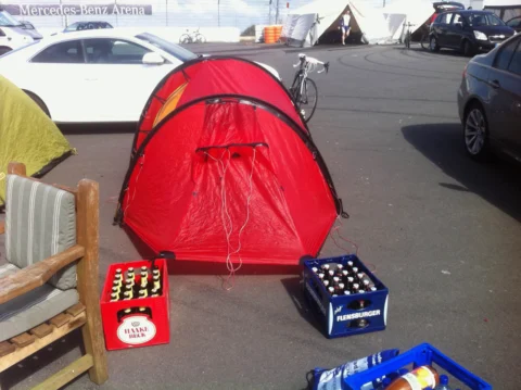 Ein rotes Zelt und Getränkekisten auf dem Parkplatz vor der Arena