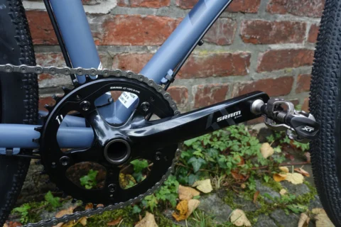 Detail des Kona Rove ST: SRAM-Kurbel und Umwerfer vor einer Backsteinwand