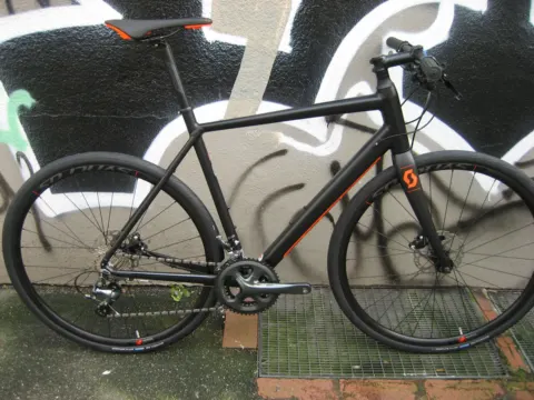 Das Scott Metrix 20 Disc in Mattschwarz von der linken Seite an einer Graffitiwand