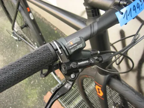 Nahaufnahme des Lenkers mit Drehgriffschalter und Bremshebel, daneben ein Preisschild