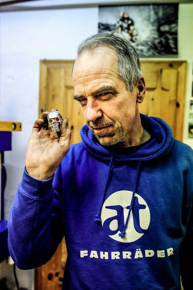 Jens Lüken im blauen at-Fahrräder-Pullover, in der Hand ein kleiner Totenkopf