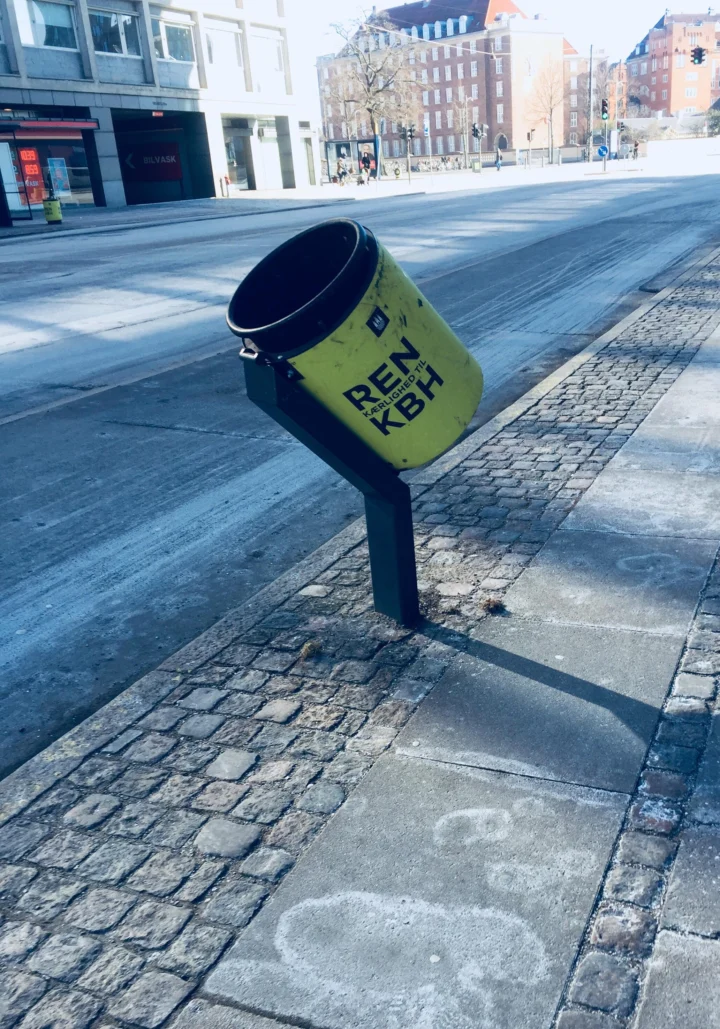Ein zur Fahrbahn geneigter Abfallbehälter am Radweg, damit er im Vorbeifahren zu treffen ist