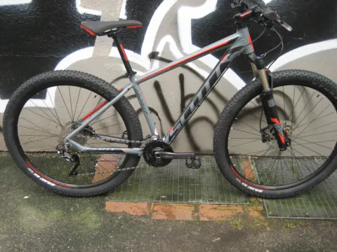 Das Scott Aspect 910 in Grau von der linken Seite an einer Graffitiwand