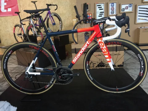 Ein rot-weißes Standert-Rennrad auf einem Podest, dahinter weitere Rahmen