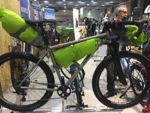 Ein Titan-Mountainbike mit grünen Bikepacking-Taschen an Lenker und Rahmen