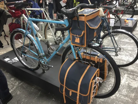 Ein hellblaues Reiserad mit Ledertaschen auf einem Podest