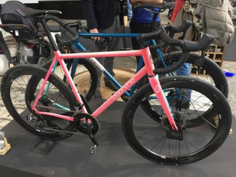 Ein rosafarbenes Gravelbike zwischen anderen Ausstellungsrädern