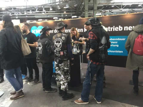 Besucher im Gespräch an einem Messestand in einer Industriehalle