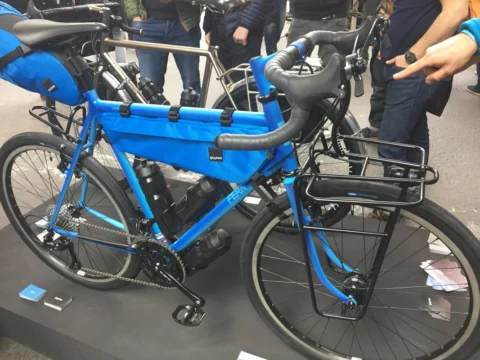 Ein blaues Reiserad mit Rahmentasche und Gepäckträgern auf der Messe