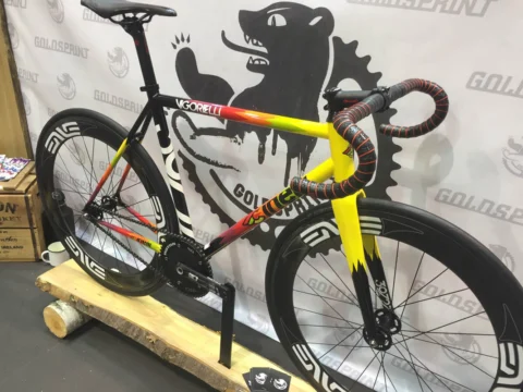 Ein bunt lackiertes Rennrad mit gelber Gabel vor einer Standwand mit Wolfsmotiv