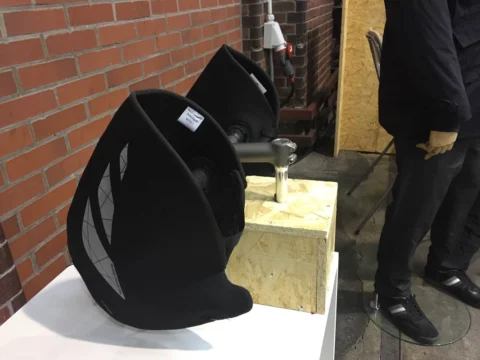 Ein schwarzer Fahrradsattel als Ausstellungsstück auf einem Sockel vor Backsteinwand