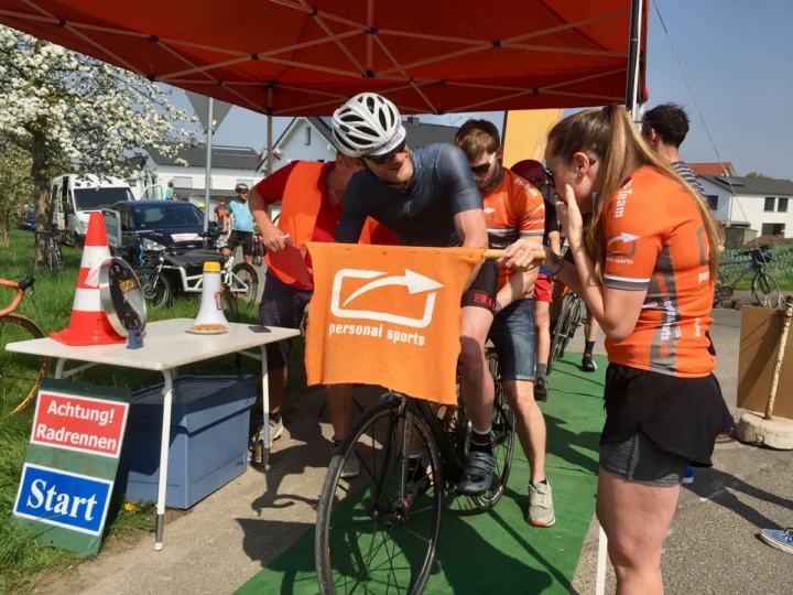 Fahrer und Helfer unter einem roten Pavillon im Start-Ziel-Bereich, davor eine Startaufsteller