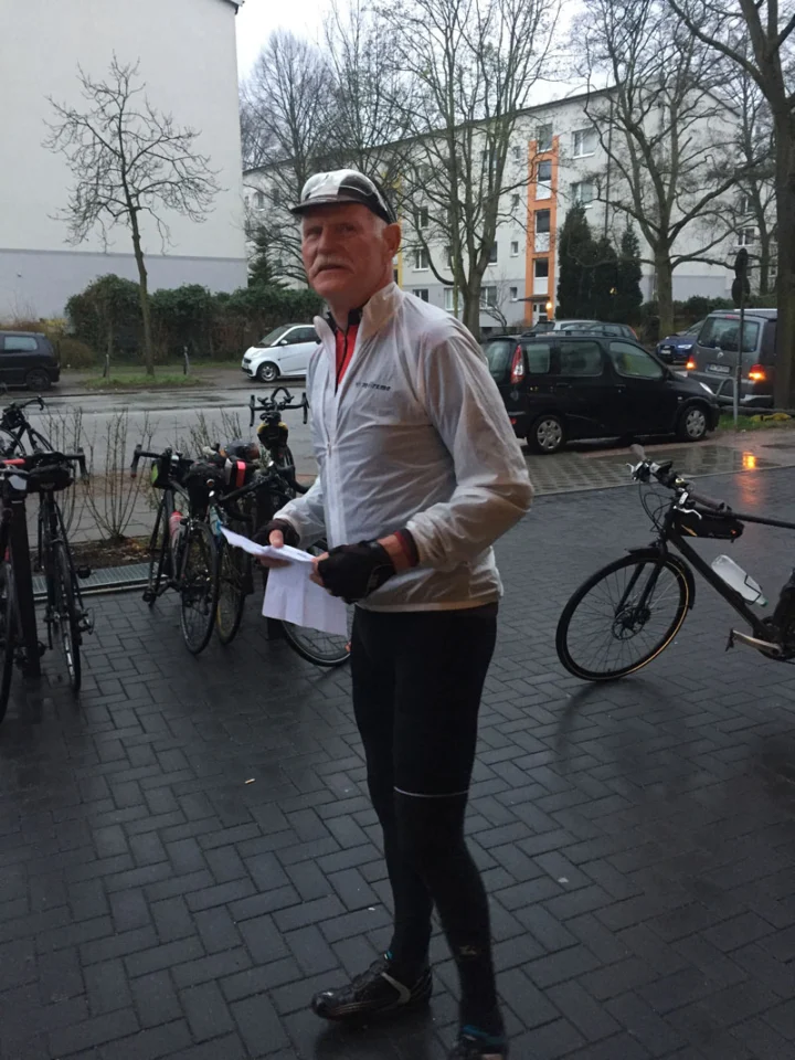 Ein Teilnehmer mit Startunterlagen im Regen, dahinter abgestellte Räder
