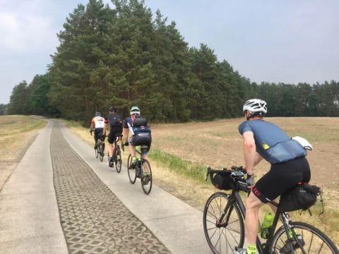 Eine Gruppe auf einem Radweg neben Kopfsteinpflaster, vorn ein Fahrer mit Lenkerrolle