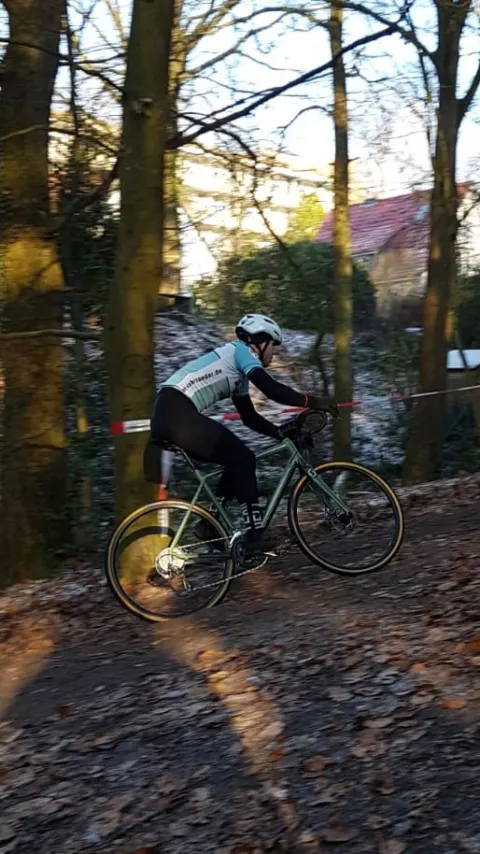 Ein Fahrer kurbelt einen bewaldeten Anstieg hinauf, der Boden aufgewühlt