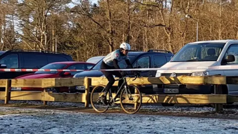 Ein Fahrer rollt an einer Reihe geparkter Autos vorbei über gefrorenen Boden