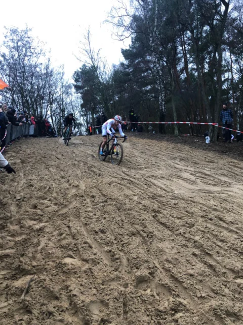Ein Fahrer im weißen Trikot fährt die Sandböschung hinunter