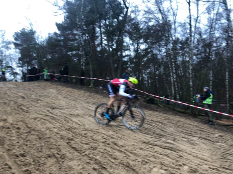 Ein Fahrer im rosa Trikot fährt eine steile Sandpassage hinunter