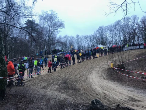 Eine lange Zuschauerreihe säumt eine breite Sandkurve im Wald