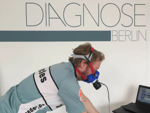 Ein Sportler mit Atemmaske während der Leistungsdiagnostik, dahinter der Schriftzug „Diagnose Berlin“
