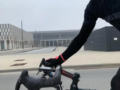 Eine Radfahrerin am Lenker, dahinter die Glasfront des Terminals