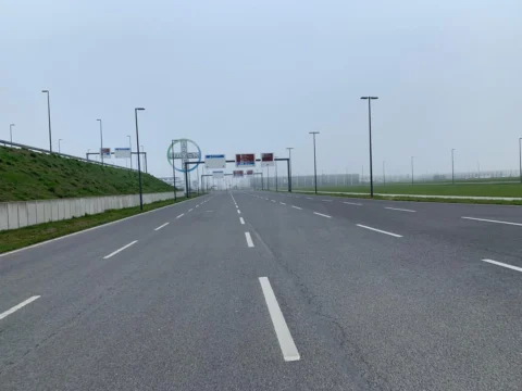 Eine leere Straße mit Schilderbrücken, am Horizont verliert sie sich im Nebel