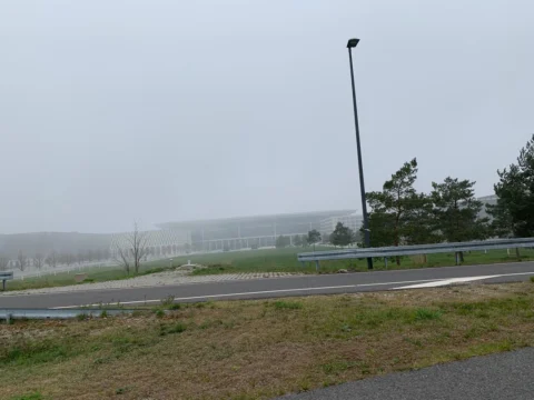 Blick über eine Leitplanke auf das Flughafengelände im Nebel
