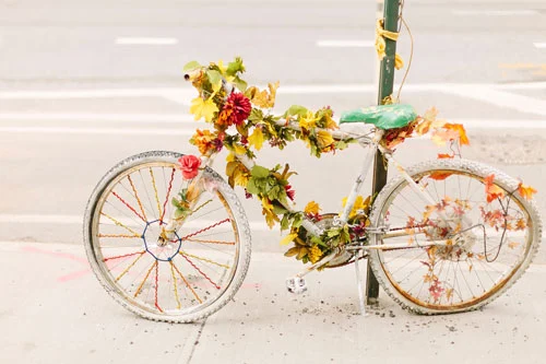 Ein weiß lackiertes Fahrrad mit Blumen als Mahnmal an einem Ampelmast