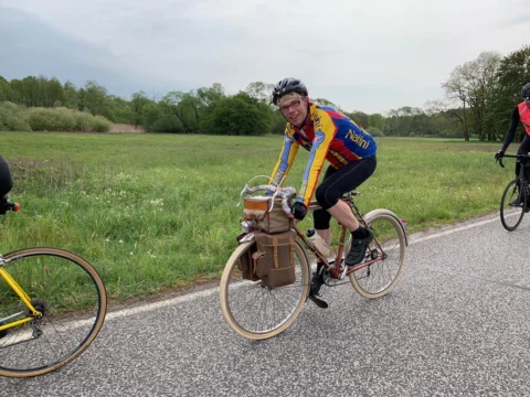 Ein Fahrer auf einem klassischen Randonneur mit Ledertaschen auf einer Landstraße