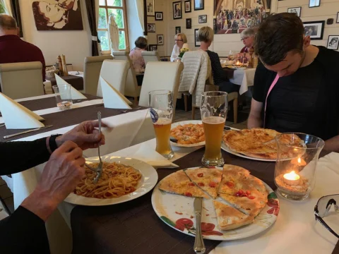 Pizza, Pasta und Weizenbier auf einem Gasthaustisch bei Kerzenschein