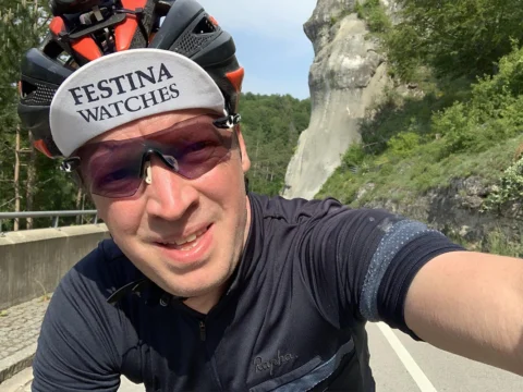 Ein Fahrer macht ein Selfie mit Rennmütze und Sonnenbrille, im Hintergrund eine Felswand