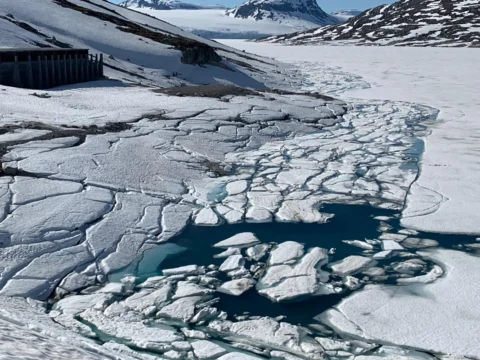 Aufbrechende Eisschollen auf dem Stausee, dazwischen türkisfarbenes Wasser