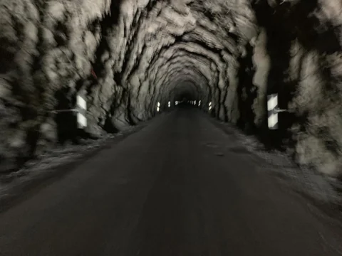 Fahrt durch einen unbeleuchteten Felstunnel, am Ende ein heller Lichtpunkt