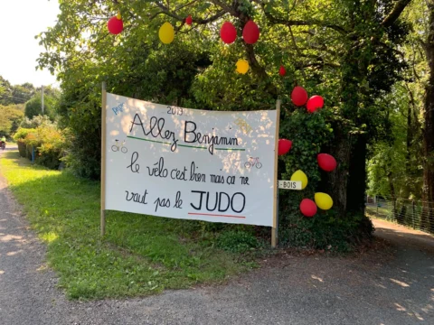 Ein handgemaltes Transparent am Straßenrand: „Allez Benjamin – le vélo c'est bien mais ça ne vaut pas le JUDO“