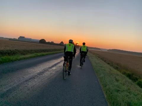 Zwei Fahrer in Warnwesten auf einer leeren Landstraße im Sonnenaufgang