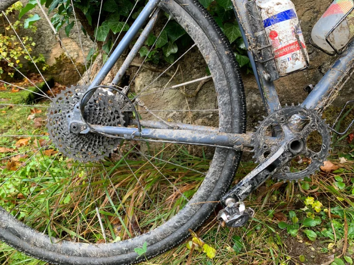 Ein verschlammtes Fahrrad im Gras, das Schaltwerk am Hinterrad verbogen