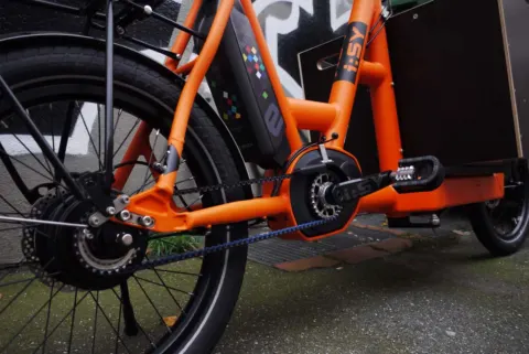 Detail des i:SY Cargo: Mittelmotor und Kettenkasten am orangefarbenen Rahmen