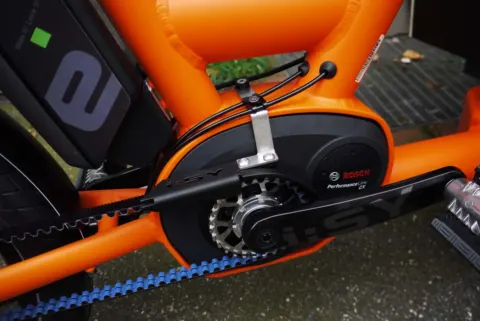 Detail des i:SY Cargo: Bosch-Mittelmotor und Zahnriemen am orangefarbenen Rahmen