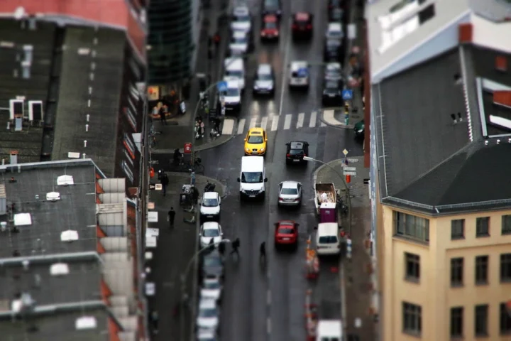 Blick von oben auf eine dicht befahrene Stadtstraße zwischen Hochhäusern