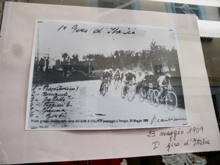 Ein historisches Foto des ersten Giro d'Italia von 1909 mit einem Feld von Rennfahrern, handschriftlich beschriftet