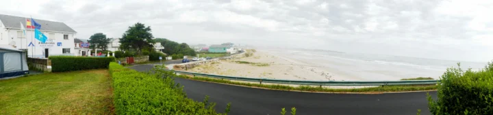 Ein Radweg an einem hellen Sandstrand entlang, links eine Häuserzeile